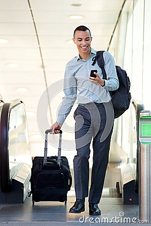 Full body young businessman walking with travel bags and mobile phone Stock Photo