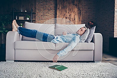 Full body profile photo of domestic handsome guy stay home quarantine time fall asleep reader book on floor lying Stock Photo