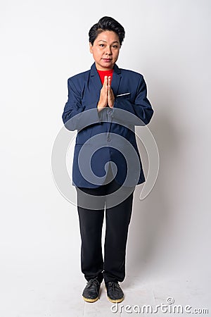 Full body shot of mature Asian businesswoman with Wai as Thai greeting Stock Photo