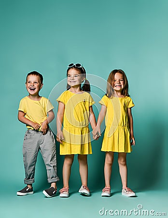 Full body shot of three children in bright clothes, two girls and one boy. Triplets, brother and sisters. Stock Photo