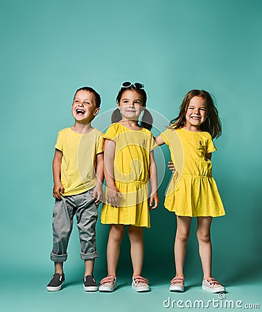 Full body shot of three children in bright clothes, two girls and one boy. Triplets, brother and sisters. Stock Photo