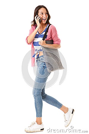 Side portrait of happy young asian woman walking with purse and talking on cellphone against isolated white background Stock Photo