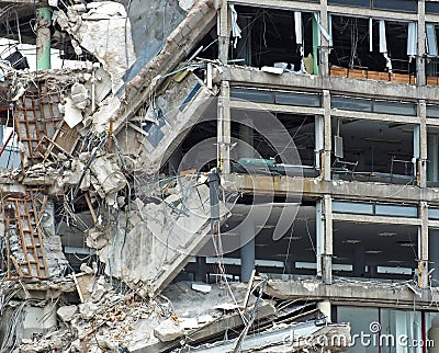 full frame image of a large destroyed collapsing building with exposed walls and smashed floors falling into rubble and tangled Stock Photo