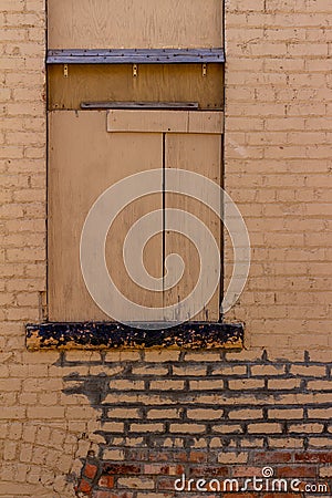 Antique brown painted exterior brick wall with boarded up window Stock Photo