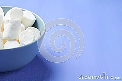 Full gray ceramic bowl of sugary white marshmallow cylindrical form on purple scratched concrete table Stock Photo