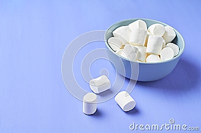 Full gray ceramic bowl of sugary white marshmallow cylindrical form on purple scratched concrete table Stock Photo