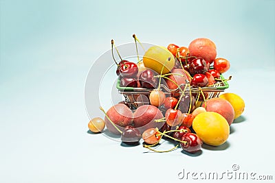 A full grocery basket with fresh fruits bananas, cherries, nectarines, apricots, peaches on a blue background Stock Photo