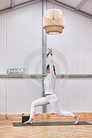 full image of attractive muscular young woman practicing hatha yoga at gym, standing barefooted on mat in Virabhadrasana 2 or Stock Photo