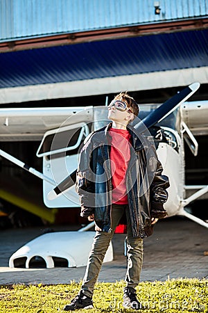 Full lenght shot of little boy in large father`s leather pilot jacket Stock Photo