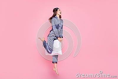 Full length body size photo of girl in sleepwear riding pillow on pajama party laughing isolated on pastel pink color Stock Photo