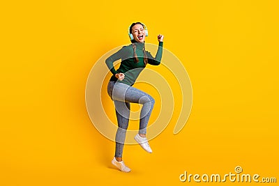 Full length body size photo overjoyed girl listening music wearing earphones singing song isolated on vivid yellow color Stock Photo