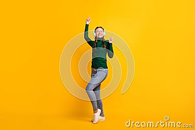 Full length body size photo overjoyed girl listening music wearing headphones dancing isolated on bright yellow color Stock Photo