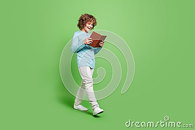 Full length body size view of attractive cheerful amazed guy reading book going isolated over vivid green color Stock Photo