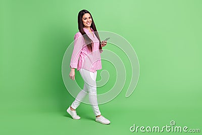 Full length body size view of attractive cheerful girl going using gadget blogging app smm isolated over green pastel Stock Photo