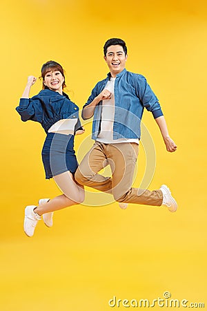 Full length body size view of nice attractive lovely cheerful cheery couple jumping up in air isolated over yellow background Stock Photo