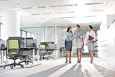 Full-length of businesswomen with file folders walking in office Stock Photo