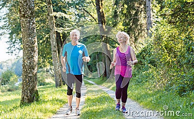 Two active seniors with a healthy lifestyle smiling while joggin Stock Photo