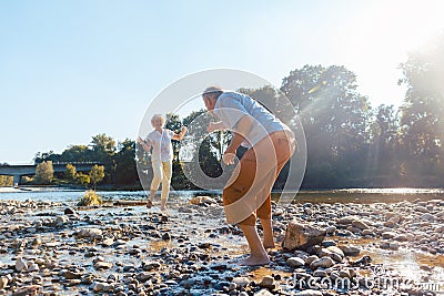 Funny senior couple playing with water at the river in a sunny day Stock Photo