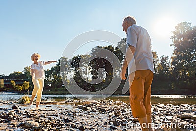 Funny senior couple playing with water at the river in a sunny day Stock Photo