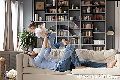 Happy young father holding little baby daughter on straight arms. Stock Photo