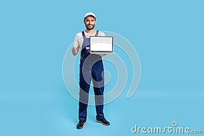 Full length high-qualified worker man in uniform showing thumbs up and holding laptop with mock up Stock Photo