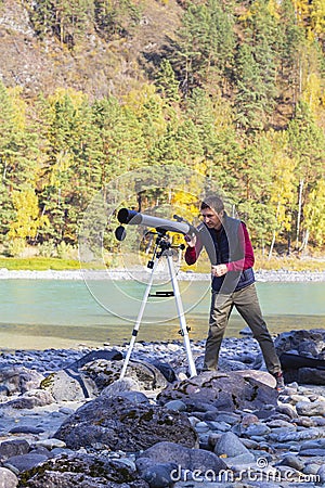 Front view,male astronomer with telescope on autumn mountain landscape background.Working on hobby Stock Photo