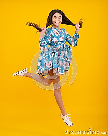 Full length overjoyed teenager kid girl 12 13 14 year jumping old on yellow background studio. Funny jump Stock Photo