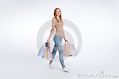 Full length photo of adorable shiny ginger lady wear beige shirt smiling walking holding bargains isolated white color Stock Photo