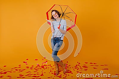 Full-length photo of amazing girl in jeans holding trendy umbrella in studio. Portrait of slim lovely lady in rubber Stock Photo