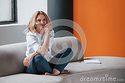 Full length photo. Businesswoman with curly blonde hair sitting in room against window Stock Photo