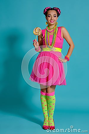 Lovely girl with a multi-colored braids hairstyle and bright make-up, posing in studio against a blue background Stock Photo