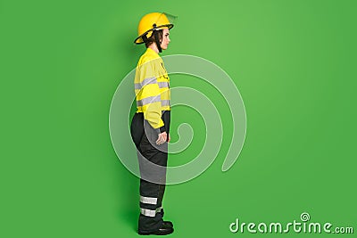 Full length photo of confident pretty firewoman dressed yellow uniform helmet looking empty space isolated green color Stock Photo
