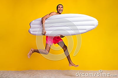 Full length photo of cool impressed shirtless man jumping high holding matrass isolated yellow color background Stock Photo