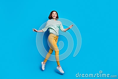 Full length photo of elegant graceful lovely cute woman dressed teal shirt yellow trousers jumping isolated on blue Stock Photo