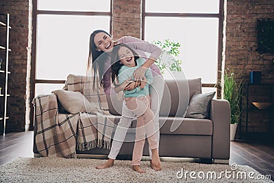 Full length photo of funky excited mommy big sister miss her sibling tickle her kid laugh loud in living room Stock Photo