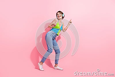 Full length photo of funky youngster girl brown bob hair dancing in club using her wireless headphones on pink Stock Photo