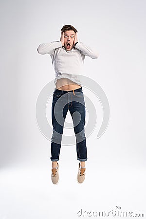 Full-length photo of funny man 30s in casual t-shirt and jeans jumping isolated over white background. Stock Photo