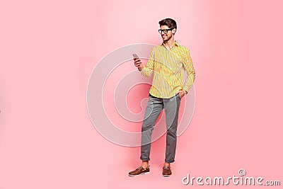 Full length photo of handsome guy typing girlfriend sms telephone addicted person wear specs hipster striped shirt pants Stock Photo