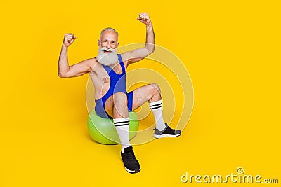 Full length photo of old funny grandfather bearded sitting wear blue sportswear showing hands up strong power muscles Stock Photo