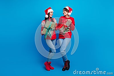 Full length photo of positive charming women santa elves wear ornament pullovers preparing x-mas gifts isolated blue Stock Photo