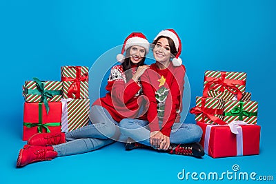 Full length photo of positive cute women santa elves wear ornament pullovers packing x-mas gifts isolated blue color Stock Photo