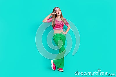 Full length photo of pretty adorable schoolgirl wear pink crop top flared pants showing v-sign isolated turquoise color Stock Photo