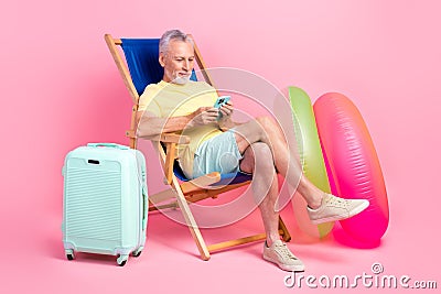 Full length photo of relaxation old man pension browsing phone send his pictures family lying sunbed isolated on pink Stock Photo