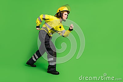 Full length photo of serious purposeful young firewoman dressed yellow uniform walking sneaking isolated green color Stock Photo