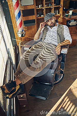 Well-dressed brunette man sitting laid-back in a barber chair Stock Photo