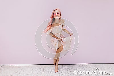 Full-length photo of slim woman with pink hair fooling around in studio. Indoor shot of barefooted Stock Photo