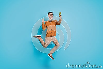 Full length photo of young excited man jump up wave hello make selfie videocall cellphone isolated over blue color Stock Photo