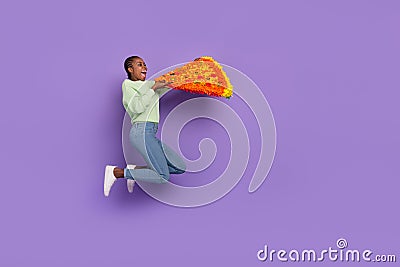 Full length picture of excited girl in trendy clothes bite huge pizza slice feeling hungry isolated on purple color Stock Photo