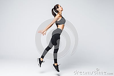 Full length of jumping fitness woman over gray background Stock Photo