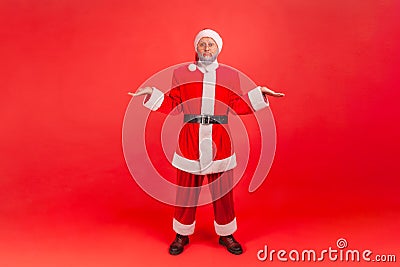 Full length portrait of elderly man with gray beard wearing santa claus costume shrugging Stock Photo